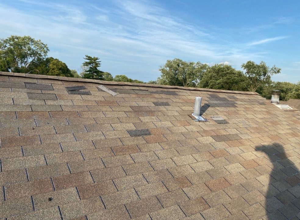 Wind Damage in St. Louis, MO — Creased and Lifted Shingles Close-up of a tan asphalt-shingle roof with several creased and lifted shingles after a wind event — St. Louis, MO