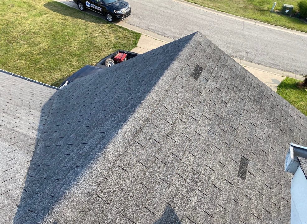 Wind Damage in St. Louis, MO — Lifted Shingles Across Roof Face Aerial view of a grey shingle roof with multiple lifted and missing shingles after a wind event — St. Louis, MO