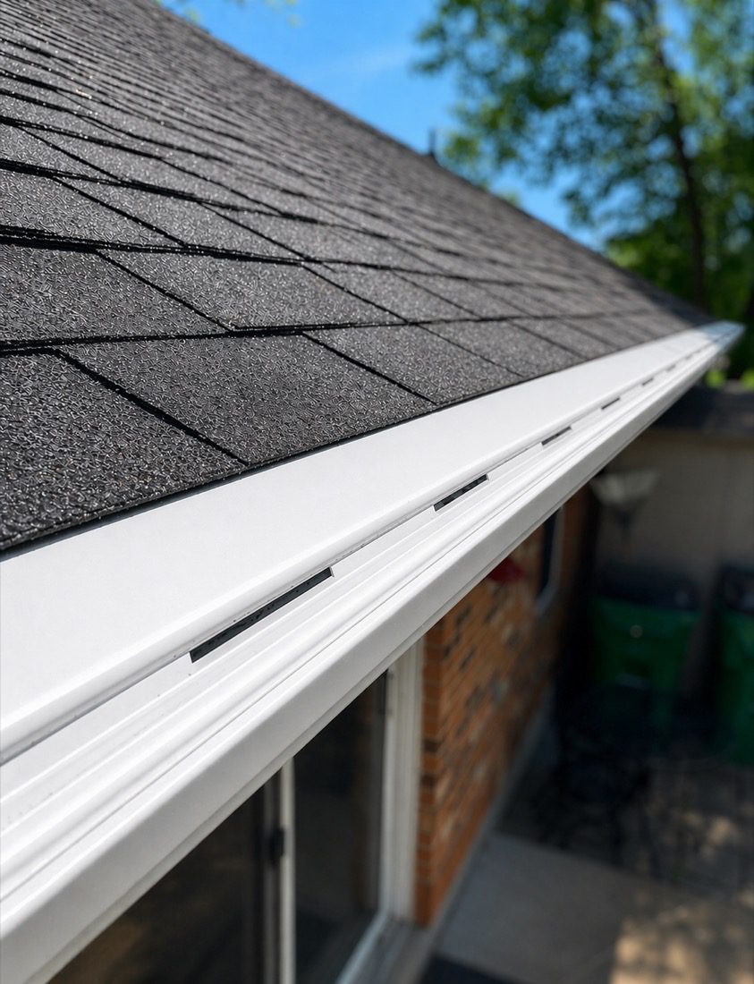 Close-up view of clean white seamless gutter installation along a shingle roof edge