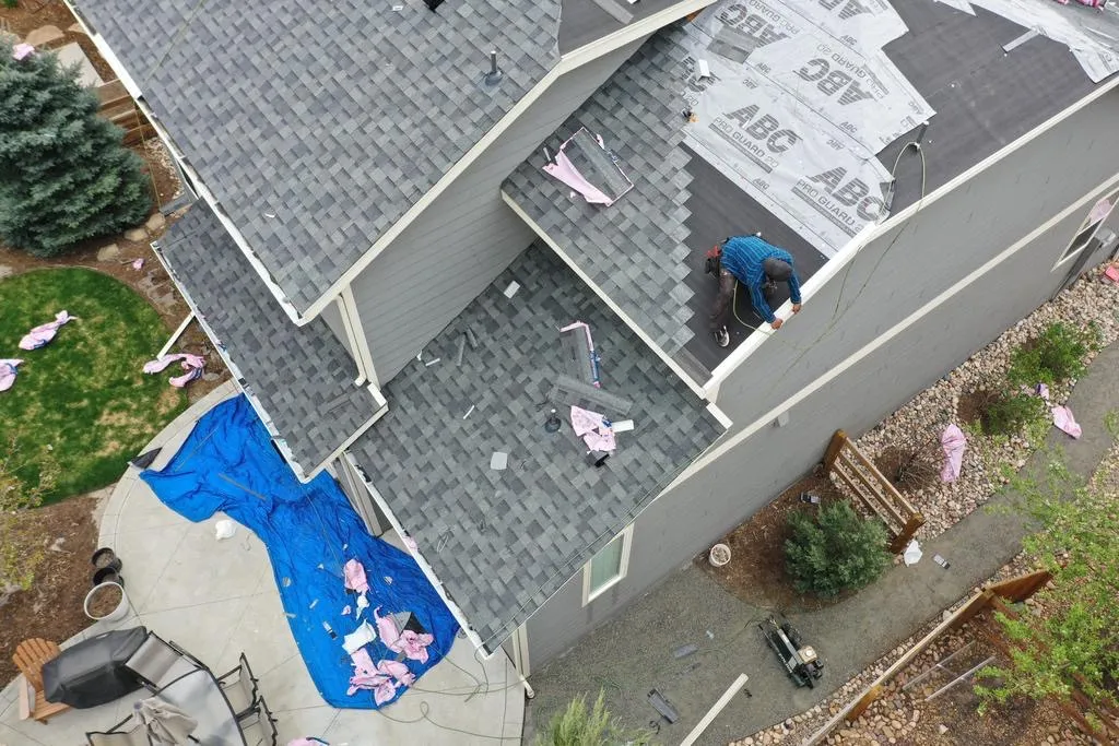 Drone Roof Progress Drone view of a two-story roof replacement with underlayment and a blue tarp.