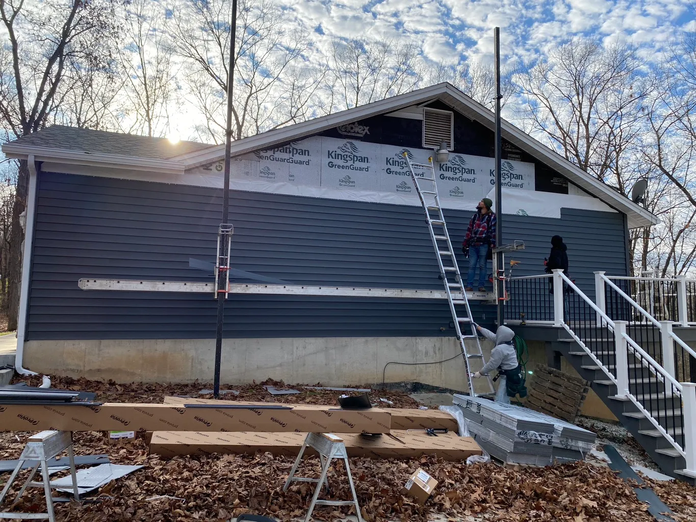 House wrap and gray siding being installed on a residential exterior wall.