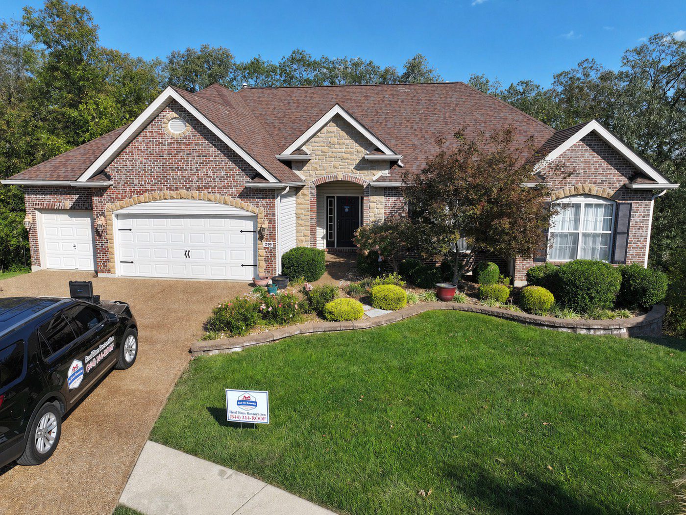 Roof Bros Restoration newly installed shingle roof on a brick house with branded yard sign