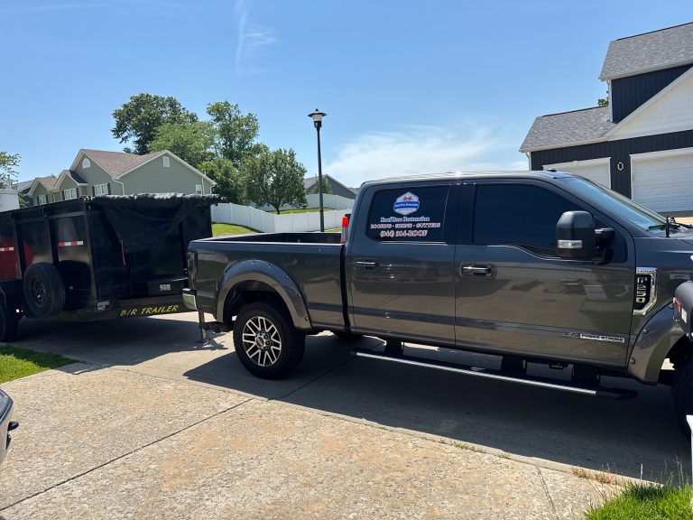 roof bros restoration branded truck 001 - Roof Bros Restoration - roofing gallery wisconsin illinois Dark gray Ford pickup truck with a Roof Bros Restoration logo decal on the door, towing a black dump trailer marked B/R TR...