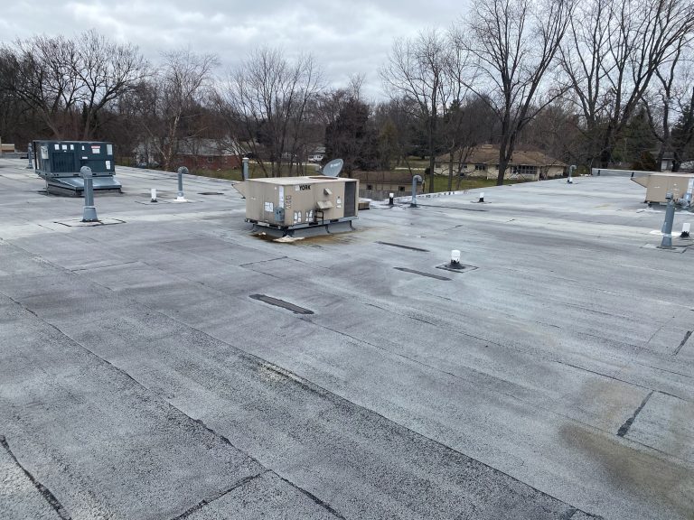 roof bros restoration illinois commercial flat roof 002 - Roof Bros Restoration - roofing gallery wisconsin illinois A wide view of a commercial flat roof with rooftop HVAC units and vents under an overcast sky, with bare trees visible in...