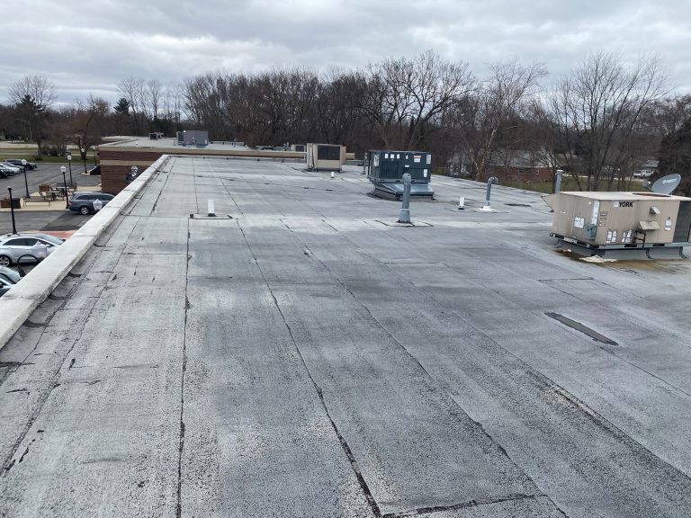 roof bros restoration illinois commercial flat roof 003 - Roof Bros Restoration - roofing gallery wisconsin illinois A commercial flat roof showing aged membrane surfaces, multiple HVAC rooftop units, and a parking lot with cars visible at...