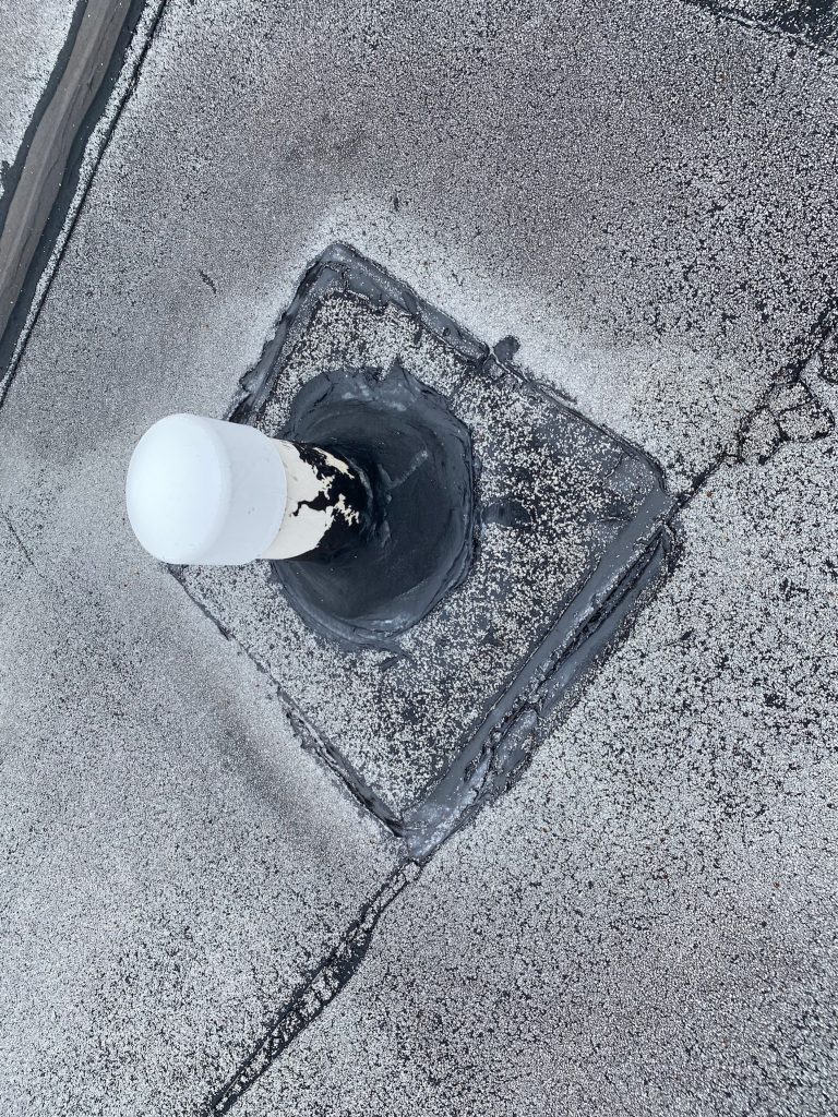 roof bros restoration illinois commercial flat roof 005 - Roof Bros Restoration - roofing gallery wisconsin illinois A close-up overhead view of a roof drain or pipe penetration on a flat commercial roof with a white capped pipe protruding...