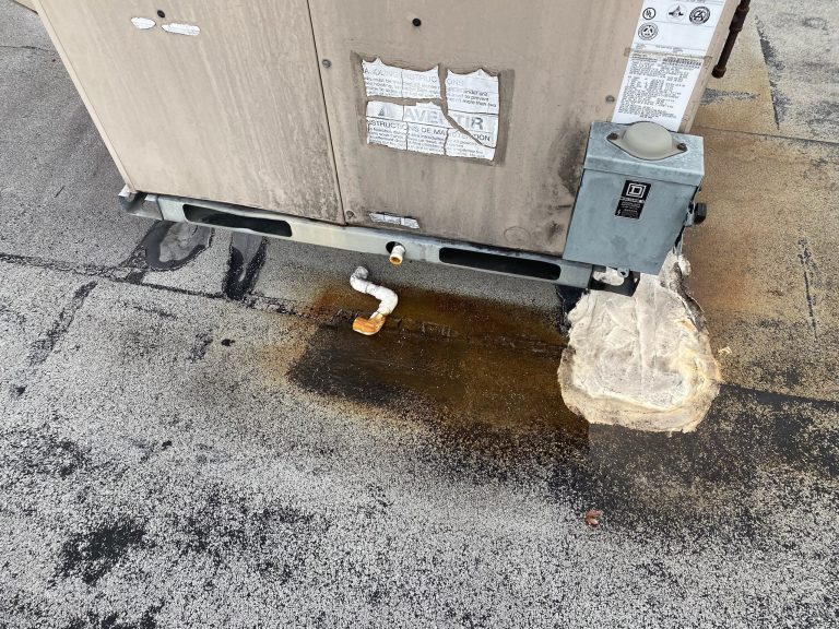 roof bros restoration illinois commercial roof leak 004 2 - Roof Bros Restoration - roofing gallery wisconsin illinois A close-up of an HVAC unit base on a flat roof showing a drain pipe, electrical disconnect box, and discolored insulation...