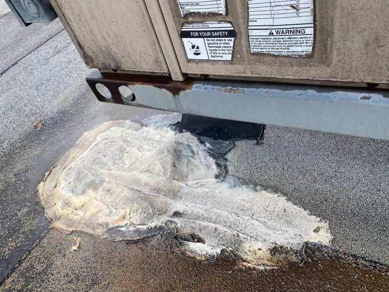 roof bros restoration illinois commercial roof leak 011 2 - Roof Bros Restoration - roofing gallery wisconsin illinois A close-up of an HVAC unit base on a flat roof showing warning labels, black sealant, and a patch of weathered white insul...