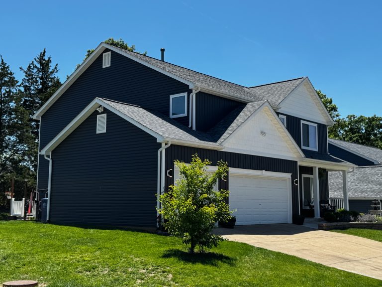 roof bros restoration illinois completed roof 007 - Roof Bros Restoration - roofing gallery wisconsin illinois A two-story home with dark navy siding, white trim, and a gray shingle roof is shown from a side angle with green lawn und...