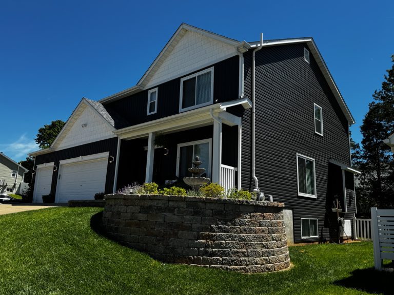 roof bros restoration illinois completed roof 008 - Roof Bros Restoration - roofing gallery wisconsin illinois A two-story home with dark navy siding and white trim features a stone-walled raised landscape bed with a fountain centerp...