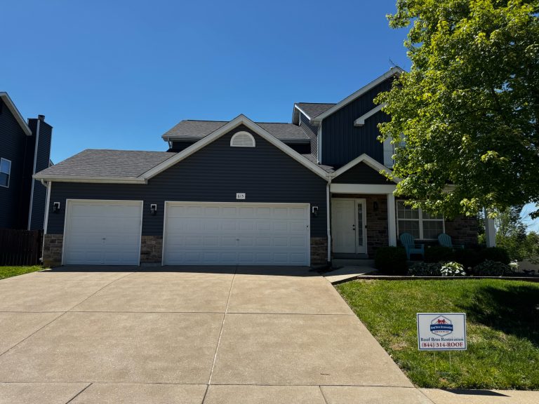 roof bros restoration illinois completed roof 010 - Roof Bros Restoration - roofing gallery wisconsin illinois Two-story residential home with dark blue siding, stone accents at the base, dark shingle roof, three-car garage, and a Ro...