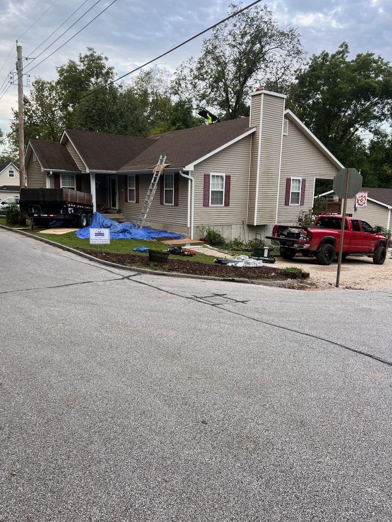roof bros restoration illinois roof install 003 - Roof Bros Restoration - roofing gallery wisconsin illinois A residential home with tan siding and dark shutters has blue tarps spread on the front lawn and a ladder against the eave...