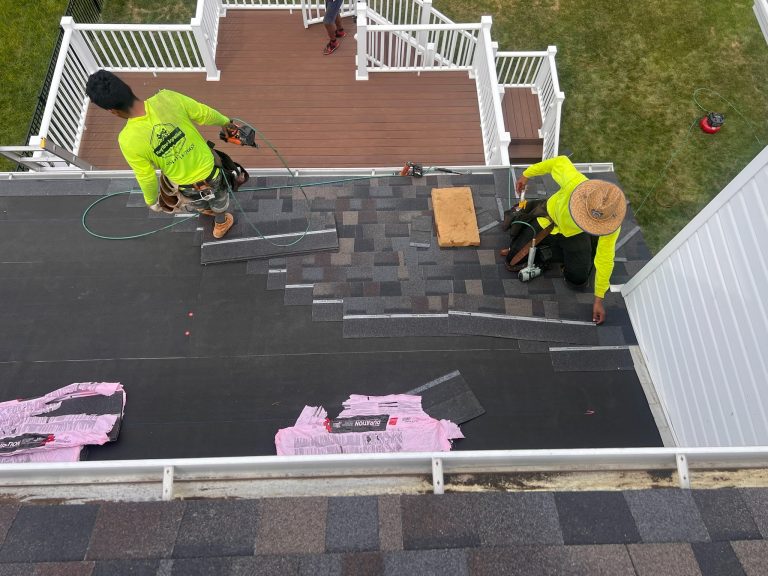 roof bros restoration illinois roof install 004 - Roof Bros Restoration - roofing gallery wisconsin illinois Two workers in yellow safety shirts install shingles on a low-slope section of roof adjacent to a white-railed deck, with...