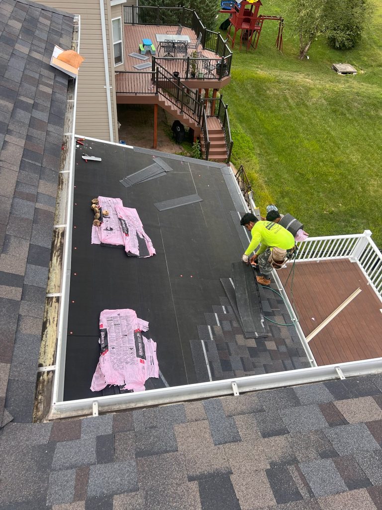 roof bros restoration illinois roof install 005 - Roof Bros Restoration - roofing gallery wisconsin illinois Two workers install shingles over black underlayment on a roof section beside a white-railed deck overlooking a backyard w...