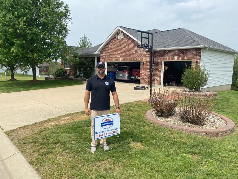 roof bros restoration illinois yard sign 001 2 - Roof Bros Restoration - roofing gallery wisconsin illinois A man wearing a dark polo holding a Roof Bros Restoration yard sign standing on a driveway in front of a brick home with a...
