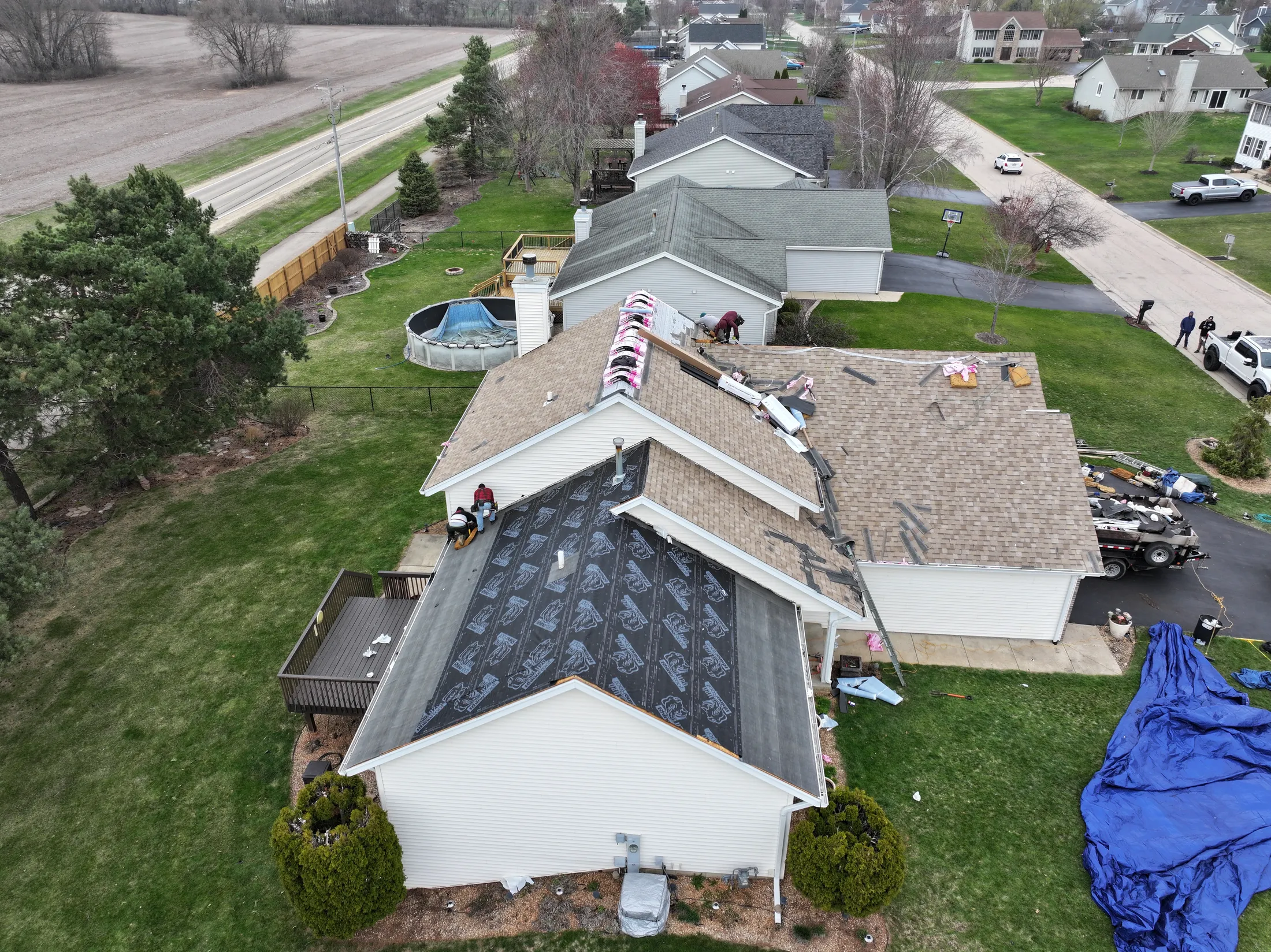 roof bros restoration madison roof replacement drone ranch mid reroof 102 - Roof Bros Restoration - Drone view of a ranch home mid re-roof with chimney saddle area exposed and crew working at the ridge — Madison, WI