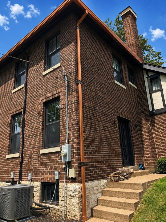roof bros restoration st louis gutter install copper half round side 001 - Roof Bros Restoration - Side view of a brick two-story home with a newly installed copper half-round gutter and downspout — St. Louis, MO
