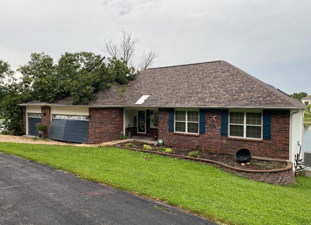 roof bros restoration st louis storm damage tree limb on home 006 - Roof Bros Restoration - insurance claim roof restoration Brick ranch home with a tree limb fallen across the corner of the roof after a storm — St. Louis, MO