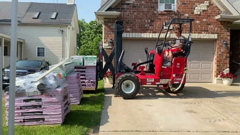 roof bros restoration video poster jobsite 018 - Roof Bros Restoration - roofing gallery wisconsin illinois A worker operates a red Moffett M8 NX piggyback forklift carrying stacked pallets of pink-wrapped shingle bundles in front...