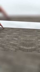 roof bros restoration video poster jobsite 020 - Roof Bros Restoration - roofing gallery wisconsin illinois Out-of-focus close-up of asphalt shingle courses on a roof with an indistinct hand or shape in the upper left, mostly blurred